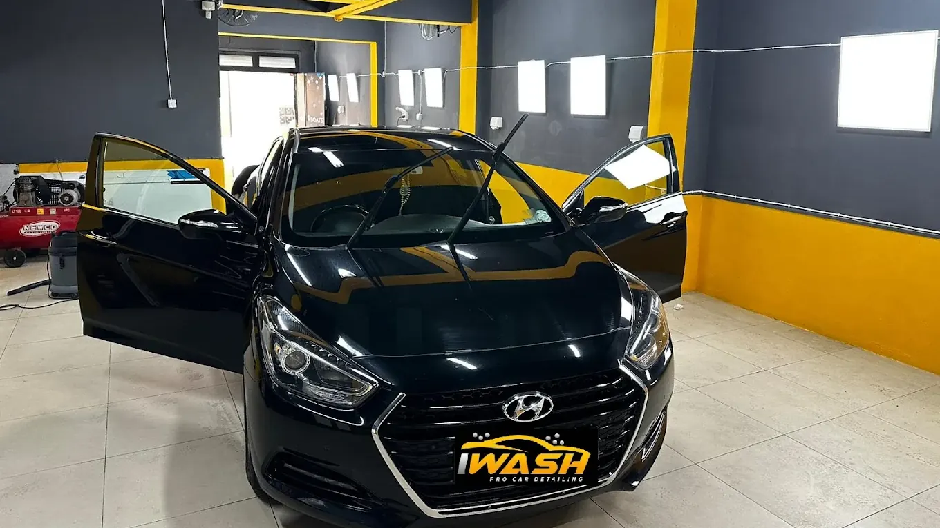 A black Hyundai saloon with all doors open under the bay lights, paint reflecting the yellow ceiling beams