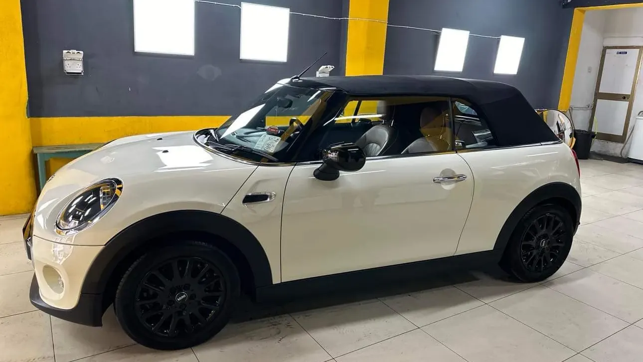 A white Mini convertible in profile on the bay floor after a full wash